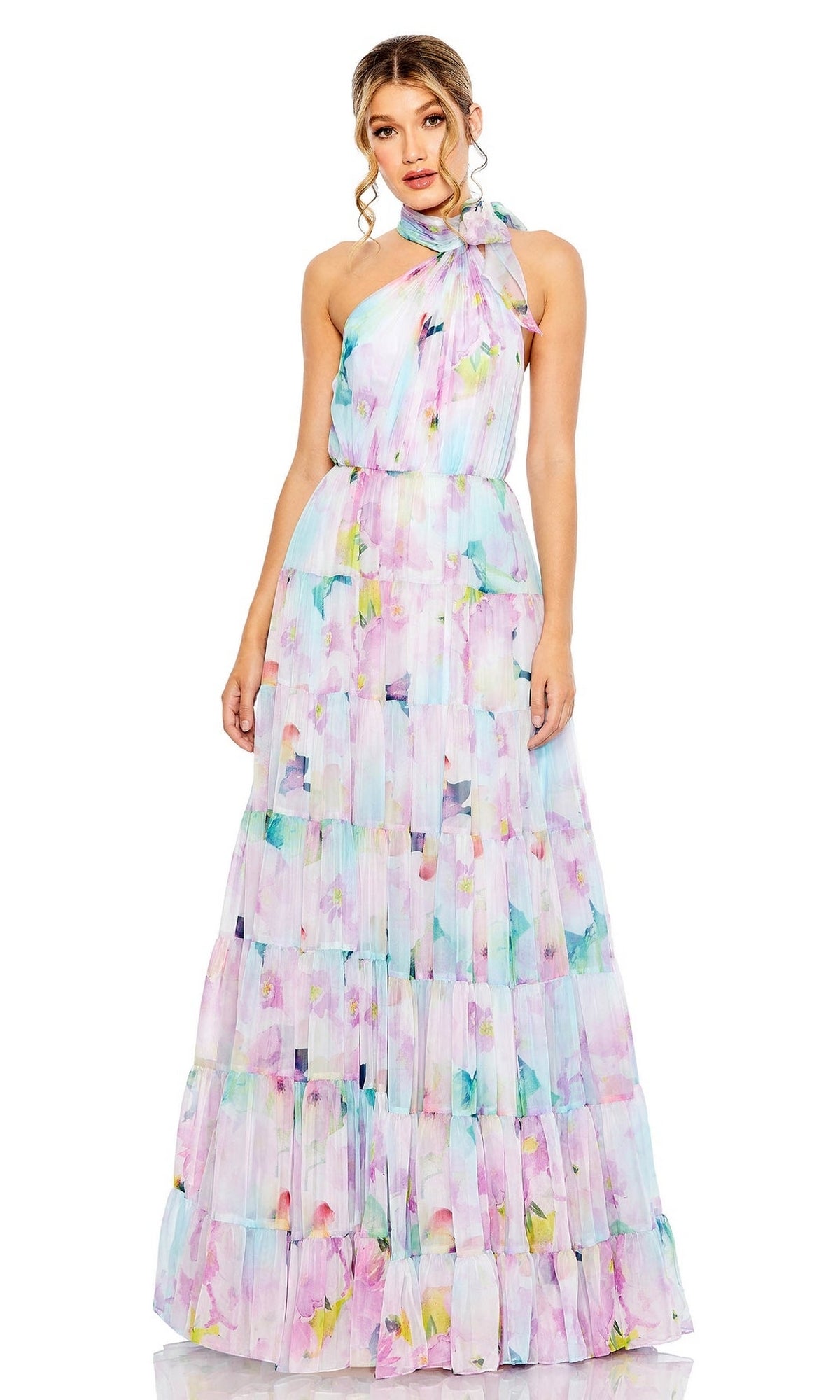 A woman wearing the Long Formal Dress 55881 by Mac Duggal, featuring a sleeveless, floor-length floral print design with a halter neckline and pleated skirt, stands against a white background.